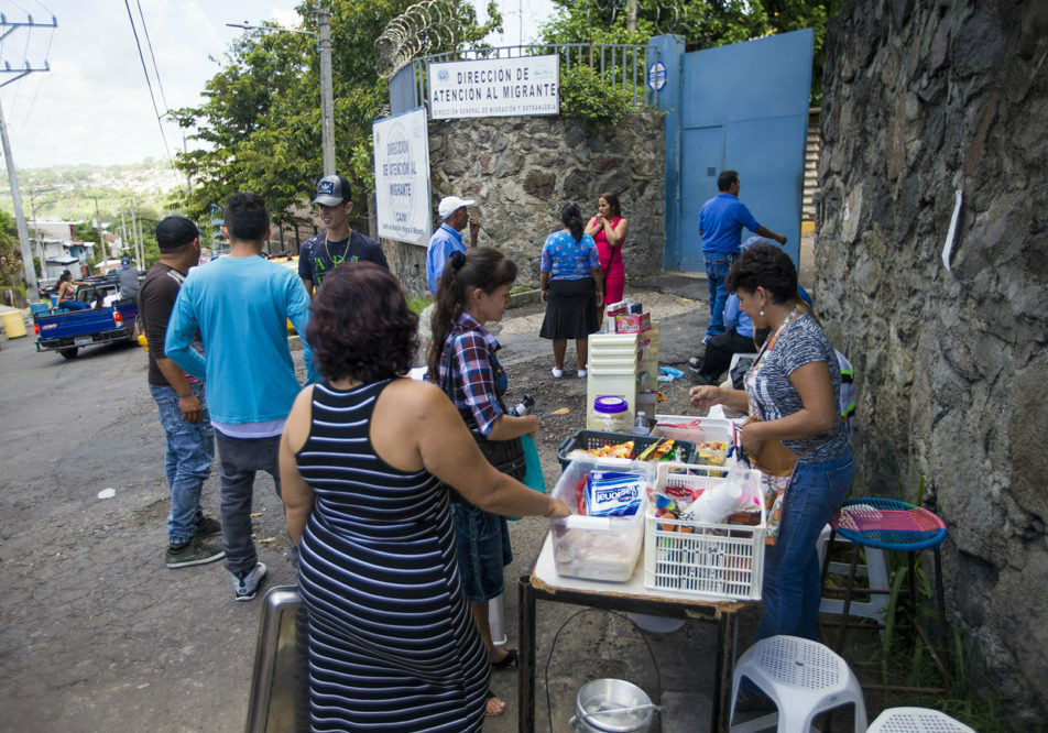 Shortly after being teleased, deportees purchase snacks and other various items from a woman set up outside of the Centro de Atención integral a Migrante (Comprehensive Migrant Care Center) in San Salvador. Photo by Jesse Costa for WBUR