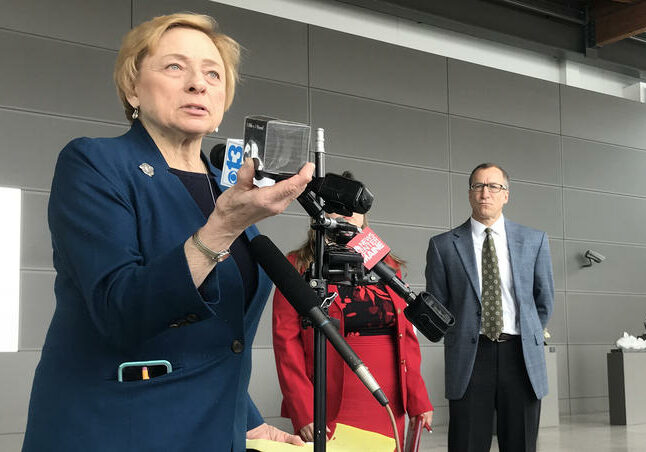 Gov. Janet Mills holds up a pound of carbon at a press conference at the Portland Jetport on Thursday. Photo by Fred Bever for Maine Public