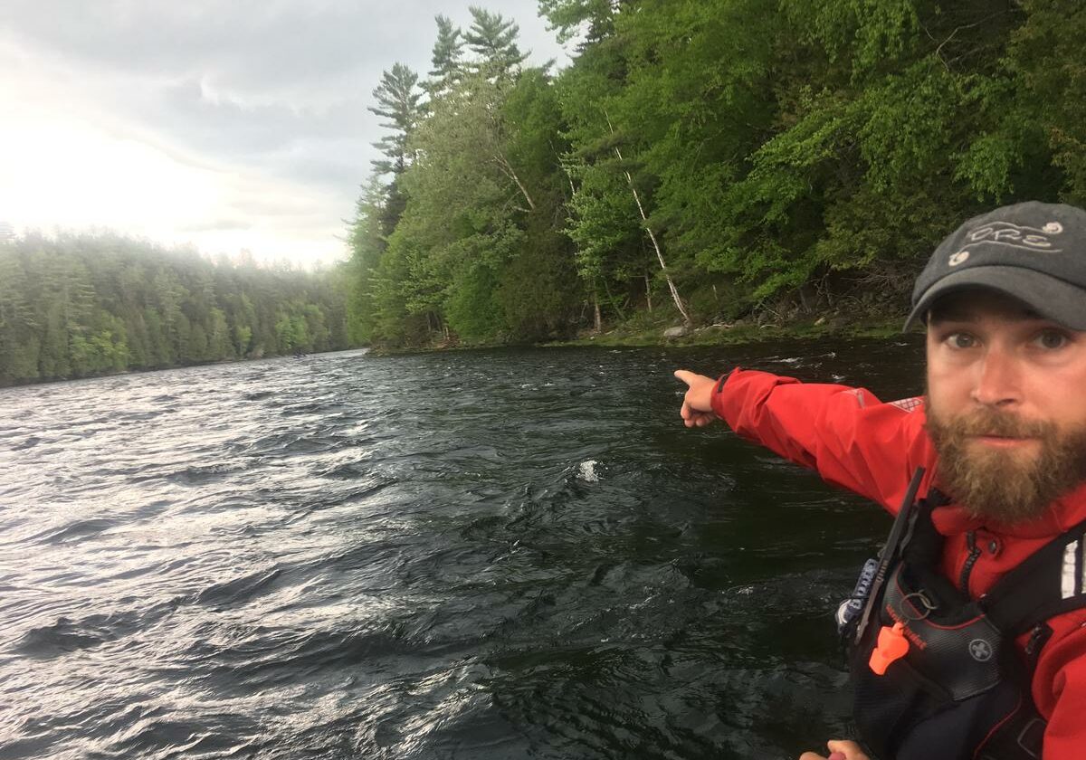 Kevin Ross, a rafting guide for Dead River Expeditions, points to a section of the Kennebec River Gorge where CMP proposes a major transmission line crossing. It would arc over an otherwise undeveloped seven mile stretch of the river. Ross opposes the plan, but CMP and other stakeholders have struck a mitigation deal that would include donations of recreational land and funding for economic development in the West Forks area. Photo by Fred Bever for Maine Public