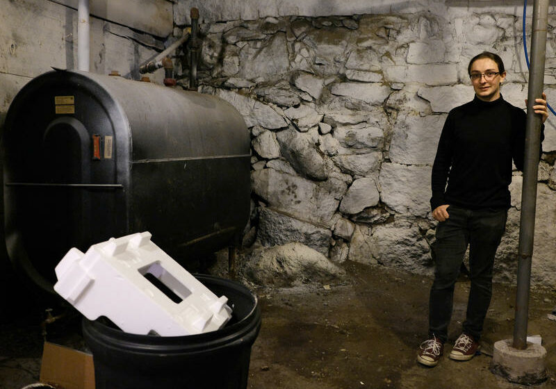 Devin Wilkie in the basement of his oil-heated home in Lebanon. Wilkie doesn't have a lot of money to spend on a more efficient heating system, he said, but he's making affordable improvements to lower his carbon footprint. Photo by Britta Greene for NHPR
