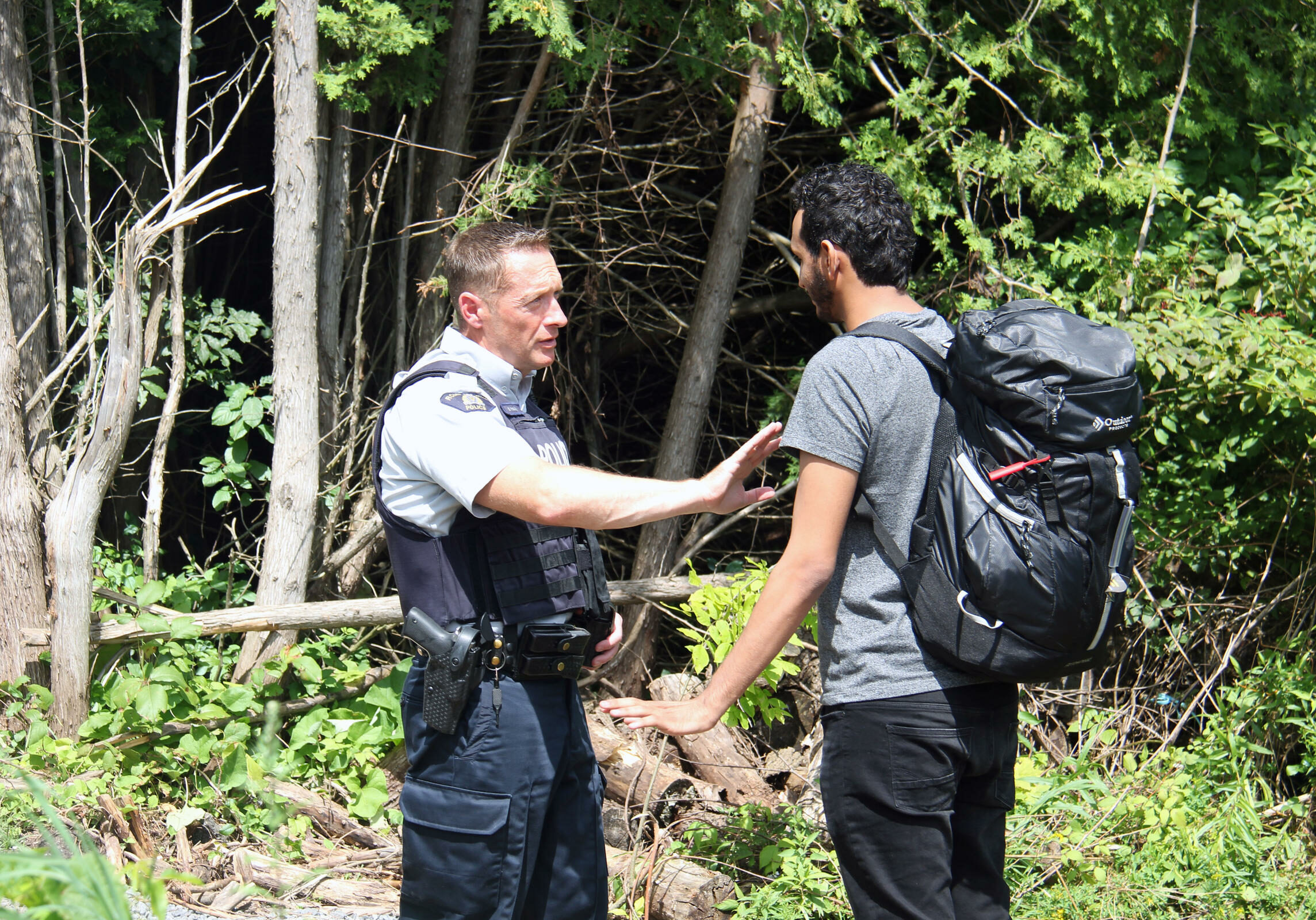 A Canadian police officer warns a young man from Yemen that if he illegally crosses into Canada in between checkpoints he will be arrested. If he proves to not be a threat to the public, the officers will help him fill out the asylum request paperwork.
Photo by Kathleen Masterson for VPR